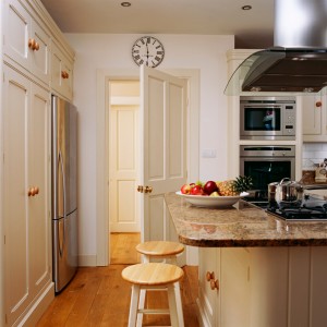 Two wooden stools are kept near the counter in an exquisite kitchen